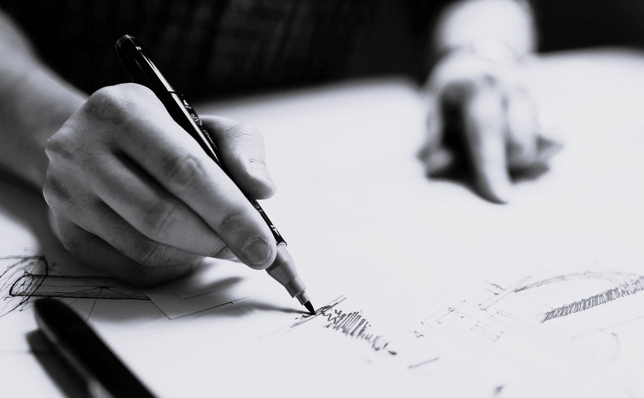 A person writing on paper with a pencil.