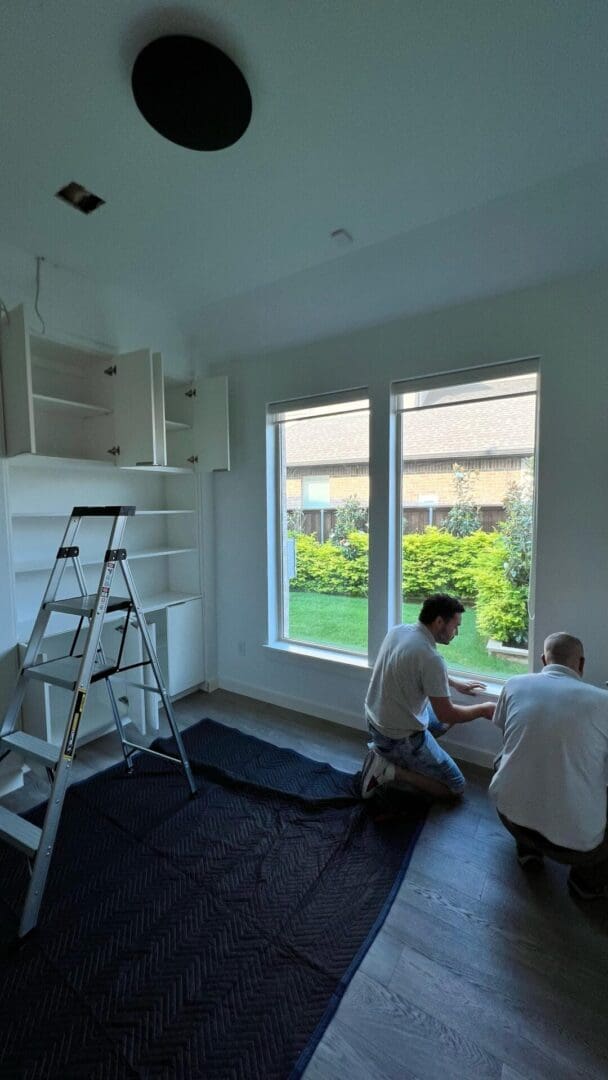 Two men are working on a window in the house.